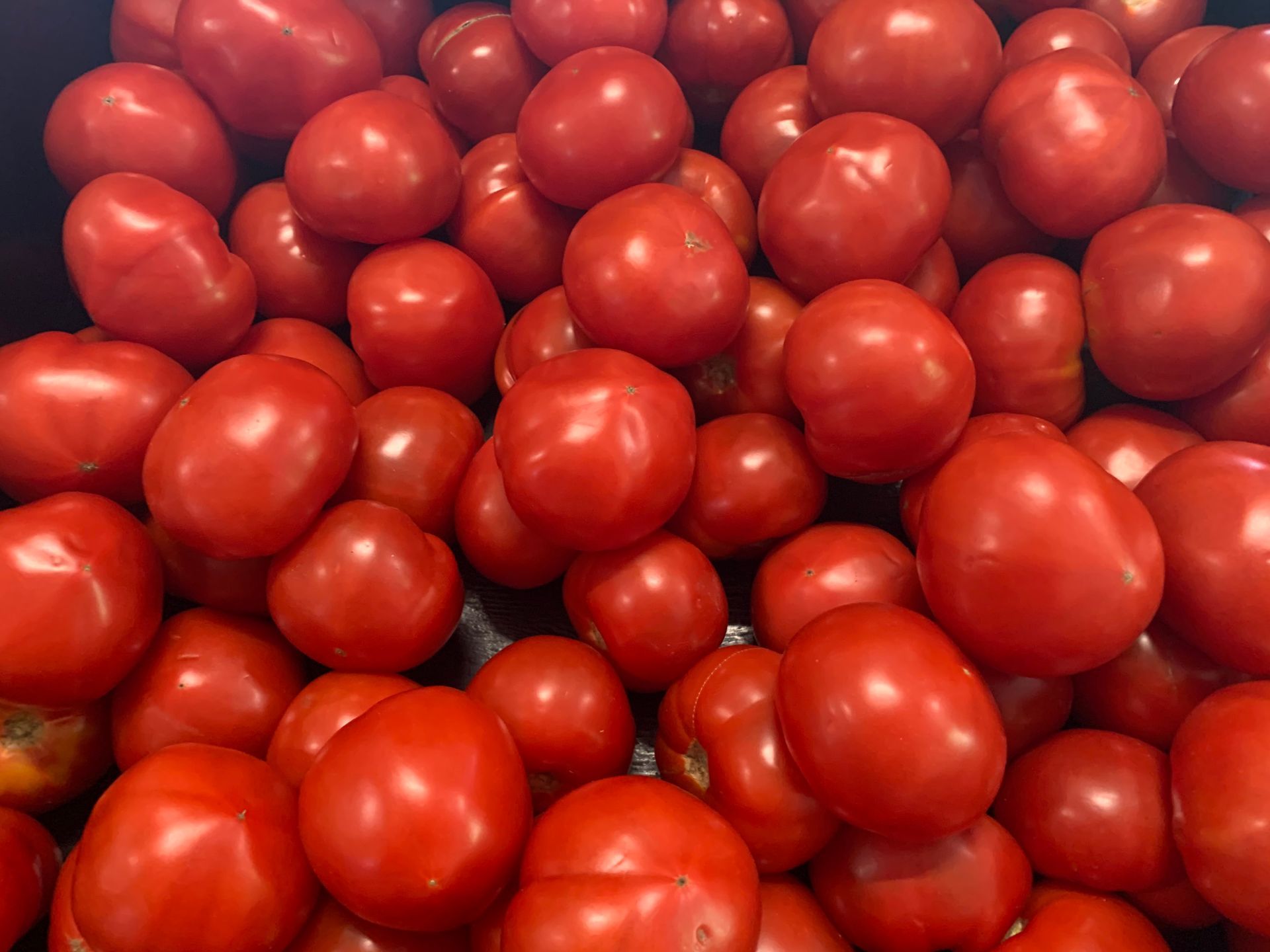 A pile of red tomatoes sitting on top of each other on a table.