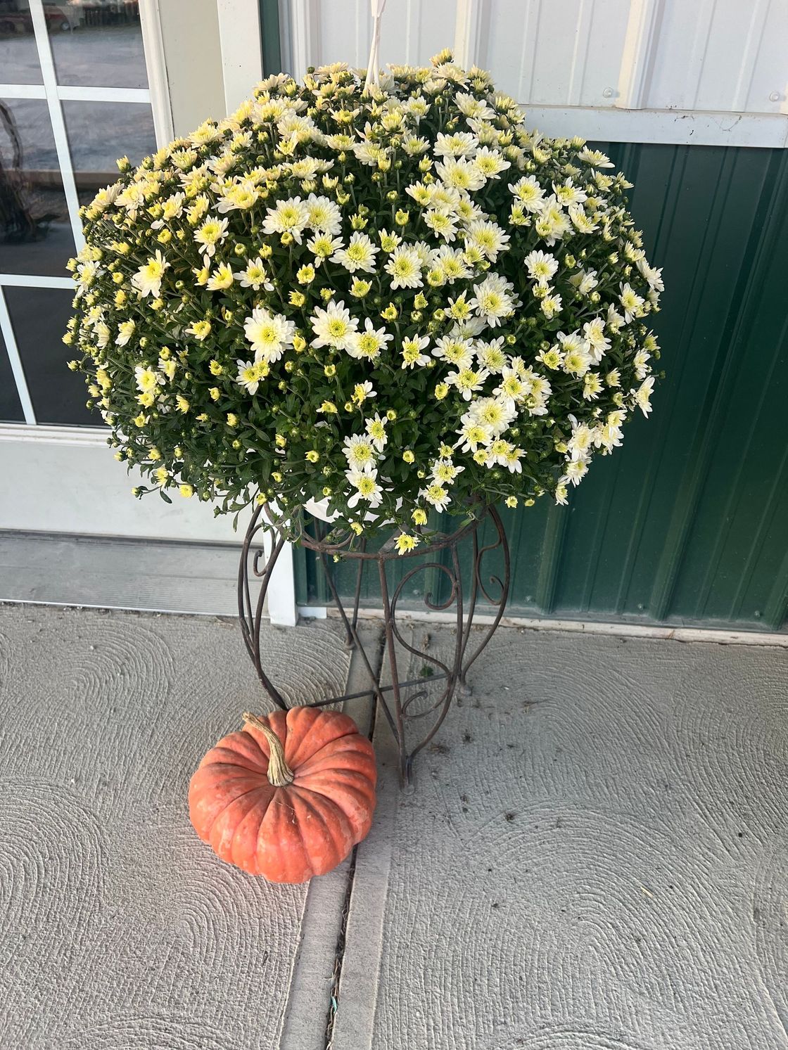 A pumpkin is sitting next to a bunch of flowers on a stand.