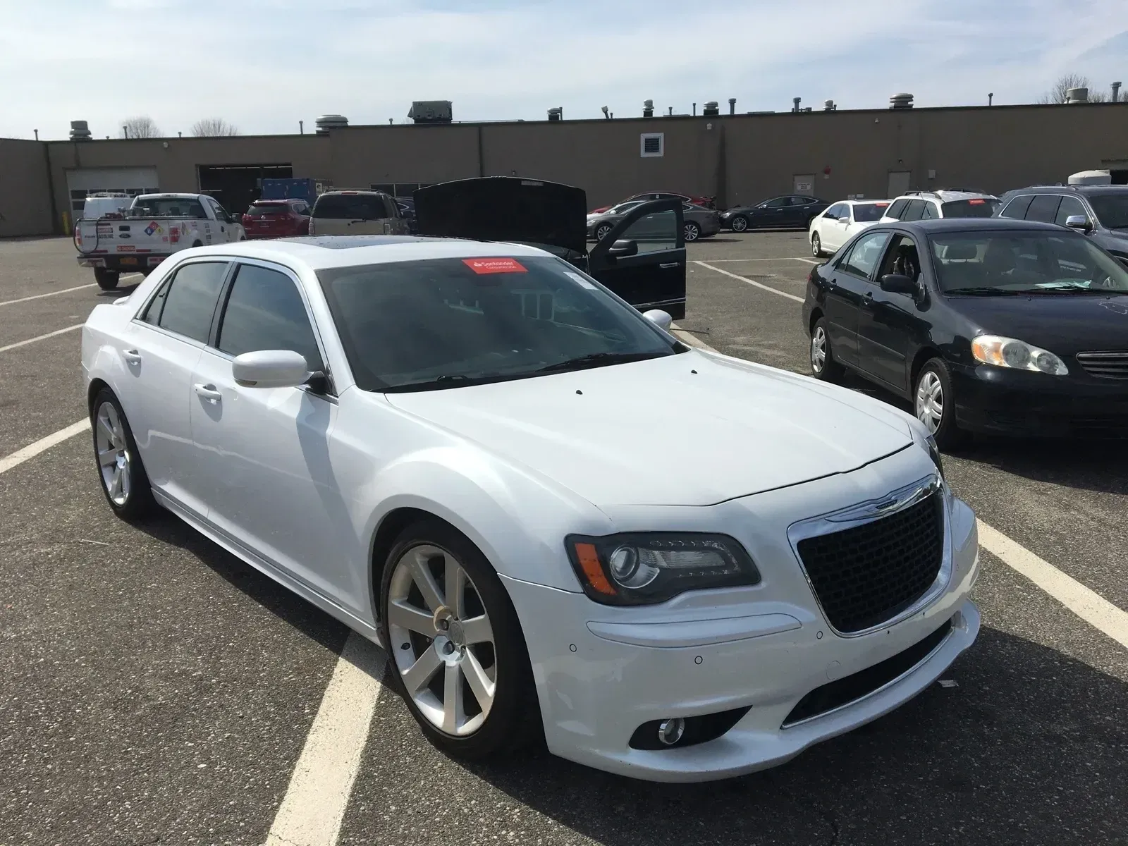 a white car is parked in a parking lot in front of a building .