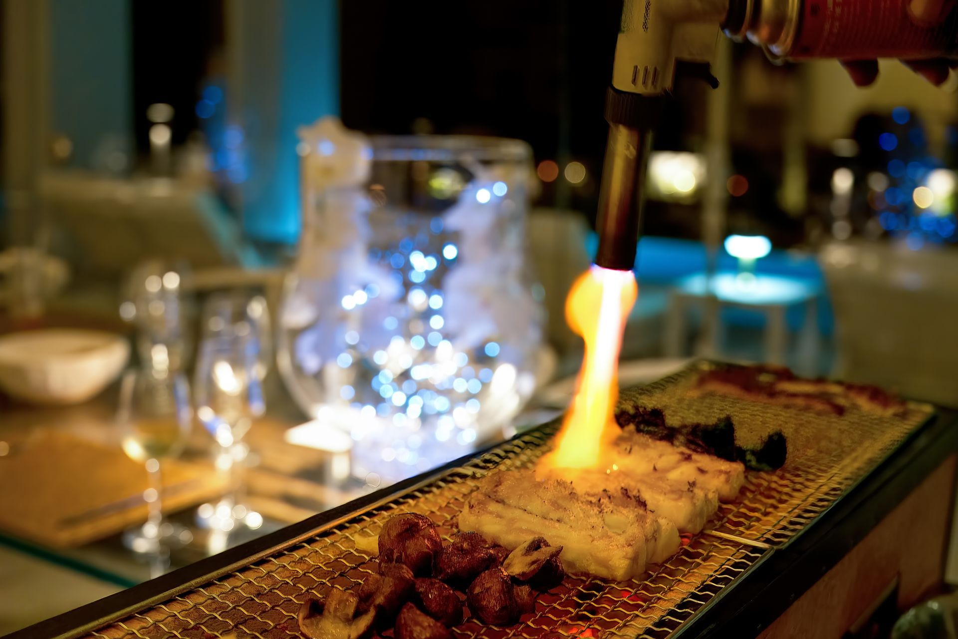 A piece of meat is being cooked on a grill with a flame coming out of it.