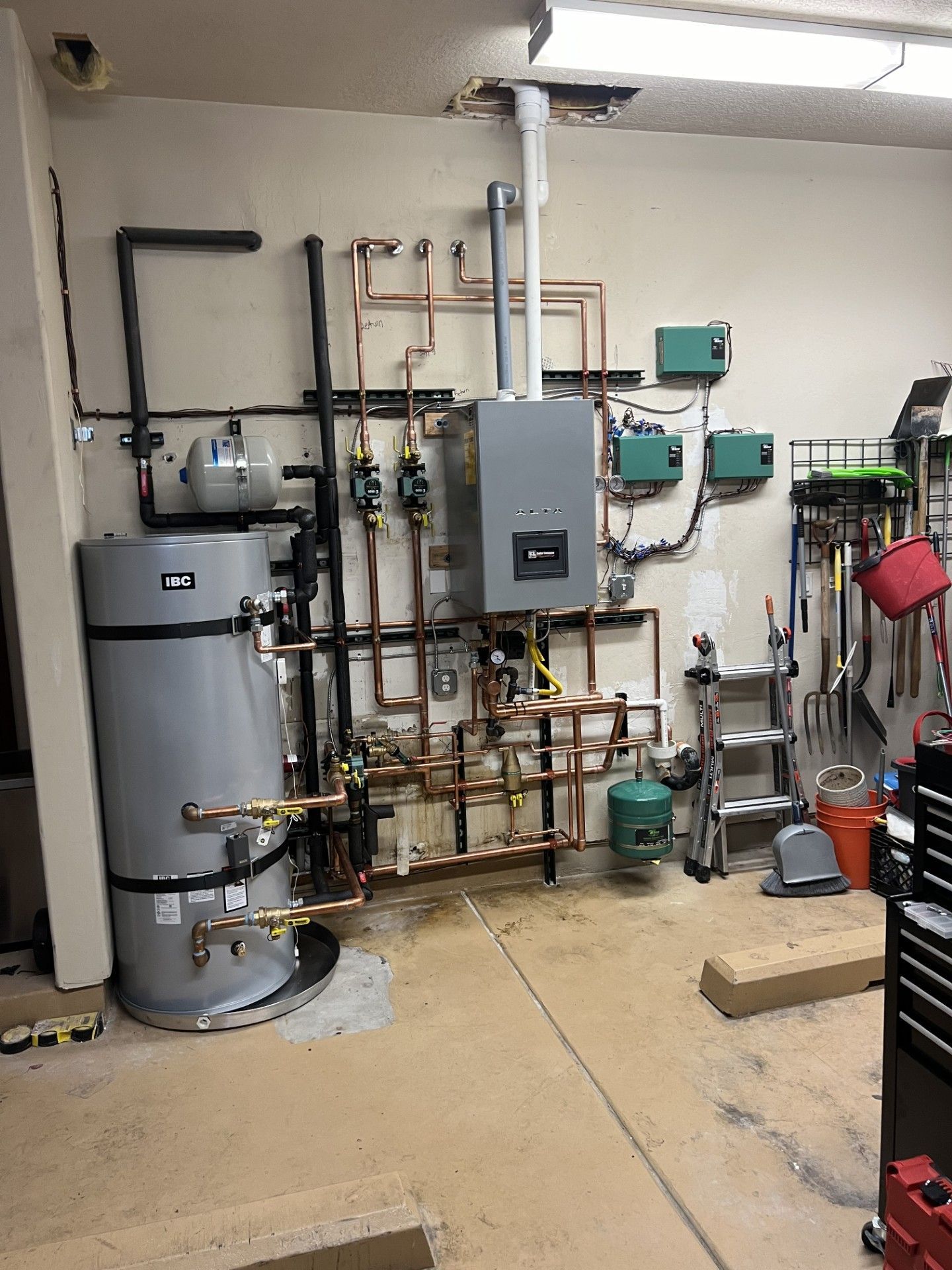 A room with a water heater and a boiler in it.