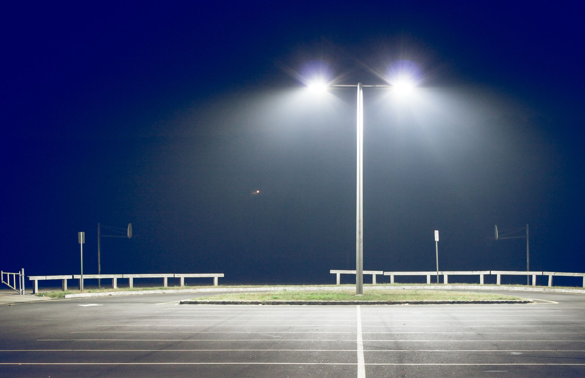 Worker in orange jumpsuit carrying an orange toolbox in a construction area.