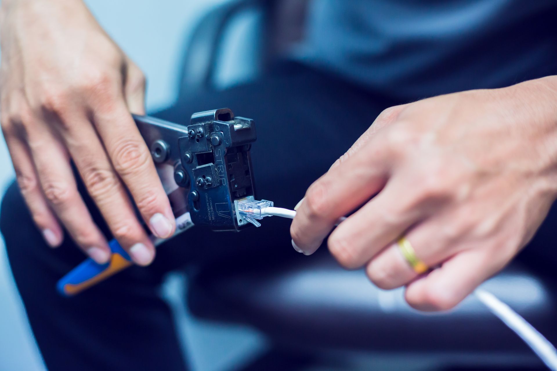 Person using crimping tool to connect an Ethernet cable.