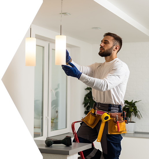 Electrician on a ladder installing a pendant light fixture.