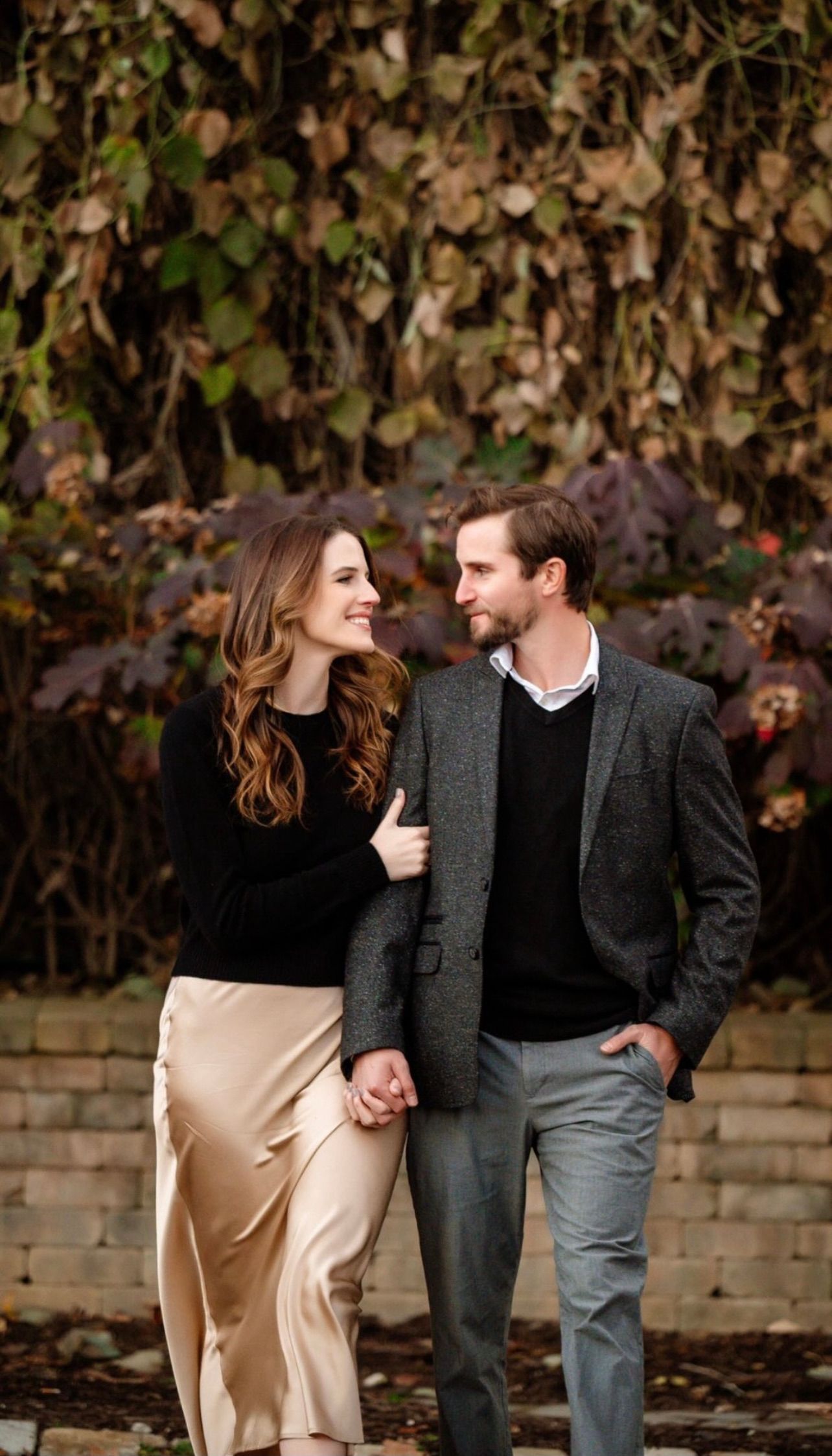 a man and a woman are holding hands and walking in front of a brick wall . natural wedding makeup. pittsburgh, pa. bridal makeup. bridal mua. wedding makeup artist. moriah e beauty. leeann marie photography.