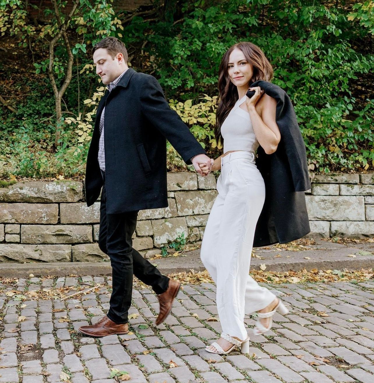a man and a woman are walking down a cobblestone street holding hands . natural wedding makeup. pittsburgh, pa. bridal makeup. bridal mua. wedding makeup artist. moriah e beauty. lauren renee photography.