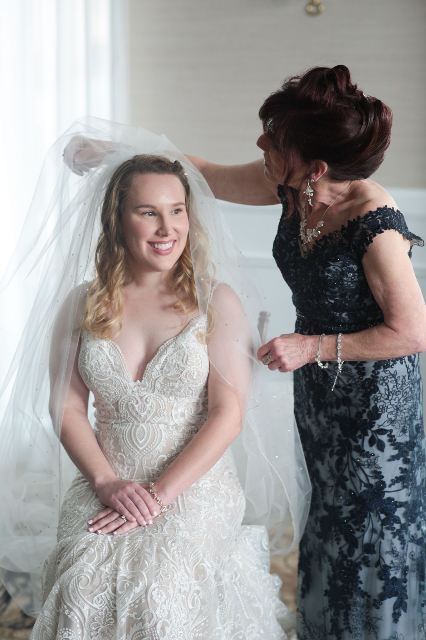 a woman is putting a veil on a bride 's head .natural wedding makeup. pittsburgh, pa. bridal makeup. bridal mua. wedding makeup artist. moriah e beauty. kristen wynn photography.