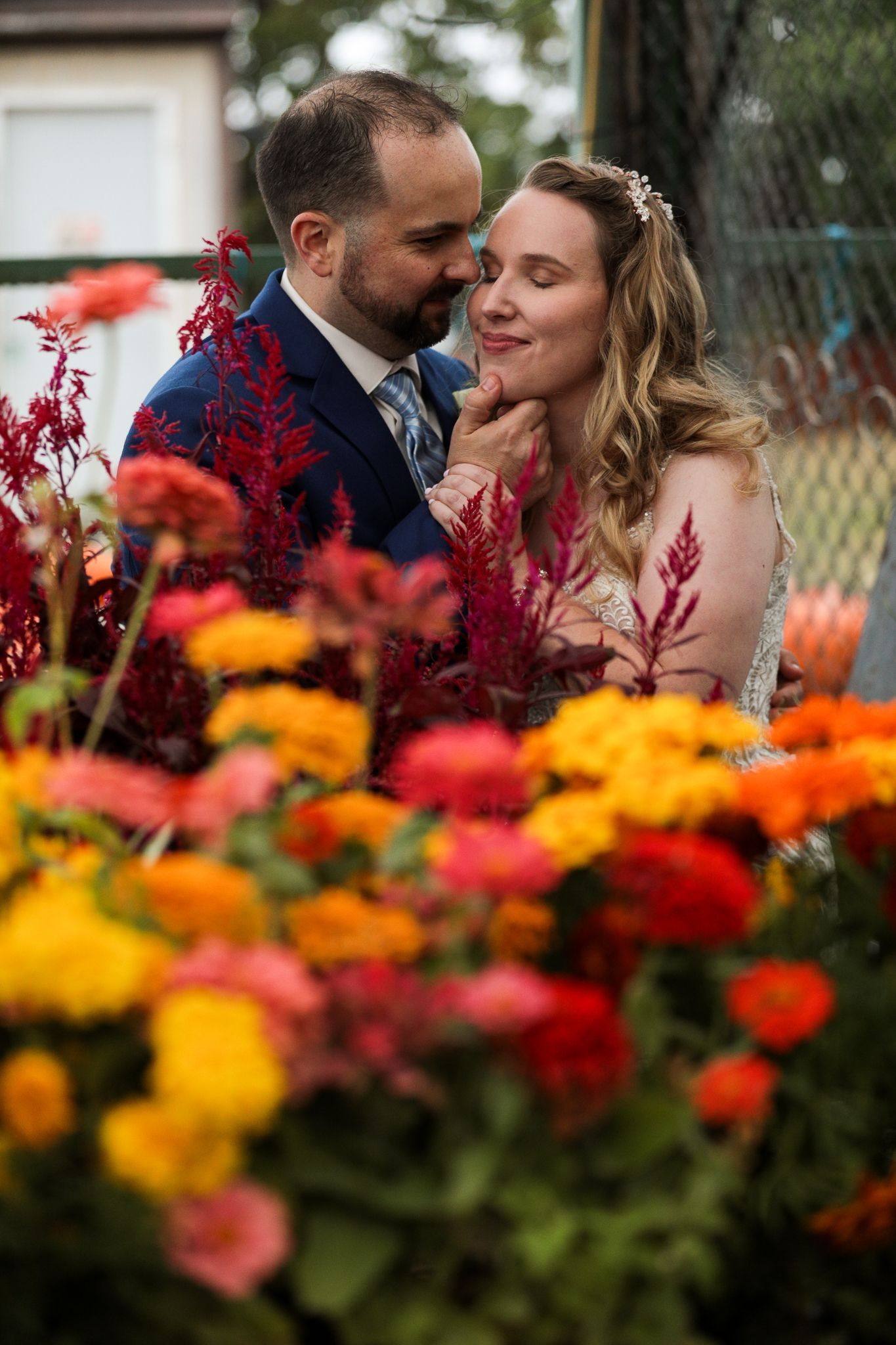 a bride and groom are posing for a picture in front of a bunch of flowers . natural wedding makeup. pittsburgh, pa. bridal makeup. bridal mua. wedding makeup artist. moriah e beauty. kristen wynn photography.