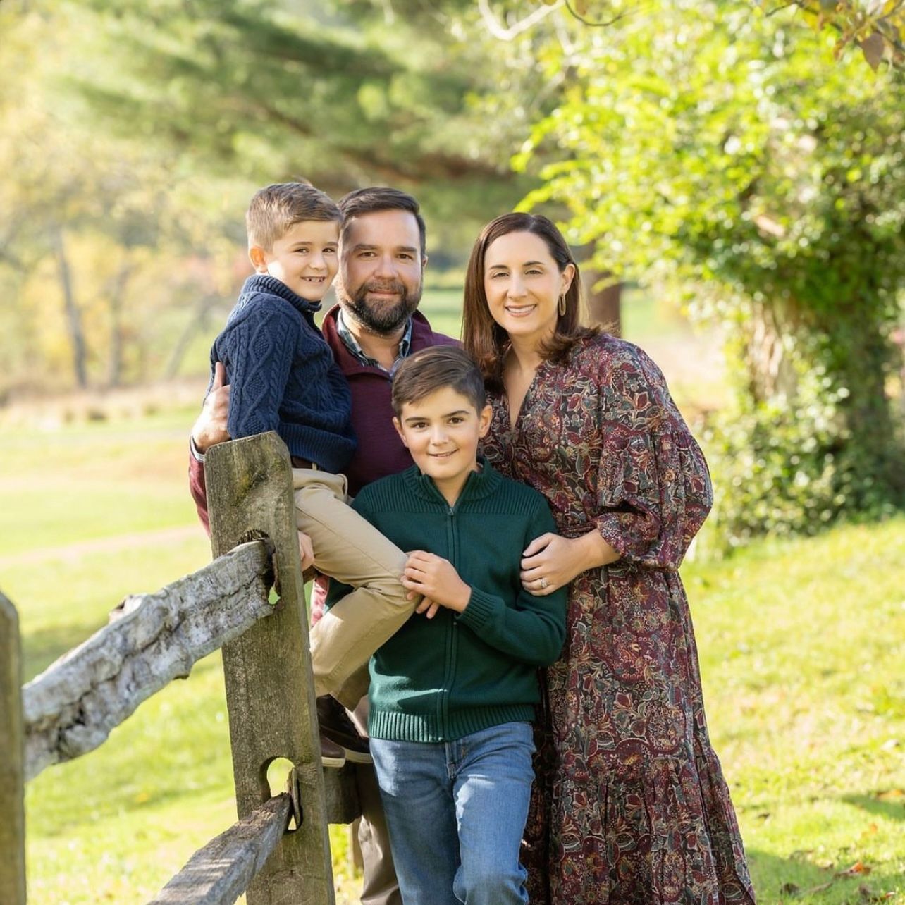 a family is posing for a picture while standing next to a wooden fence . natural makeup. pittsburgh, pa. family photos makeup. bridal mua. wedding makeup artist. moriah e beauty. kristin merck photography.