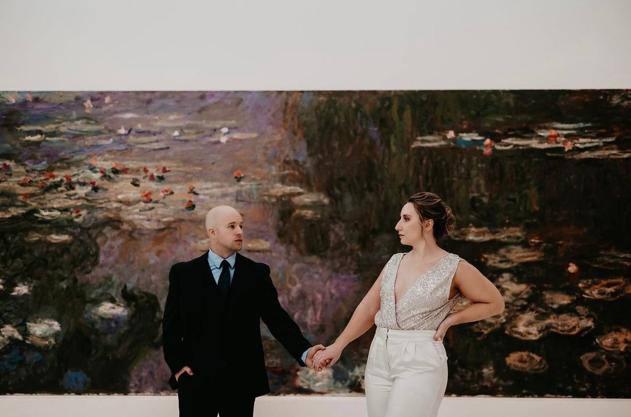 a bride and groom are holding hands in front of a painting . natural wedding makeup. pittsburgh, pa. bridal makeup. bridal mua. wedding makeup artist. moriah e beauty. drzaga photo.