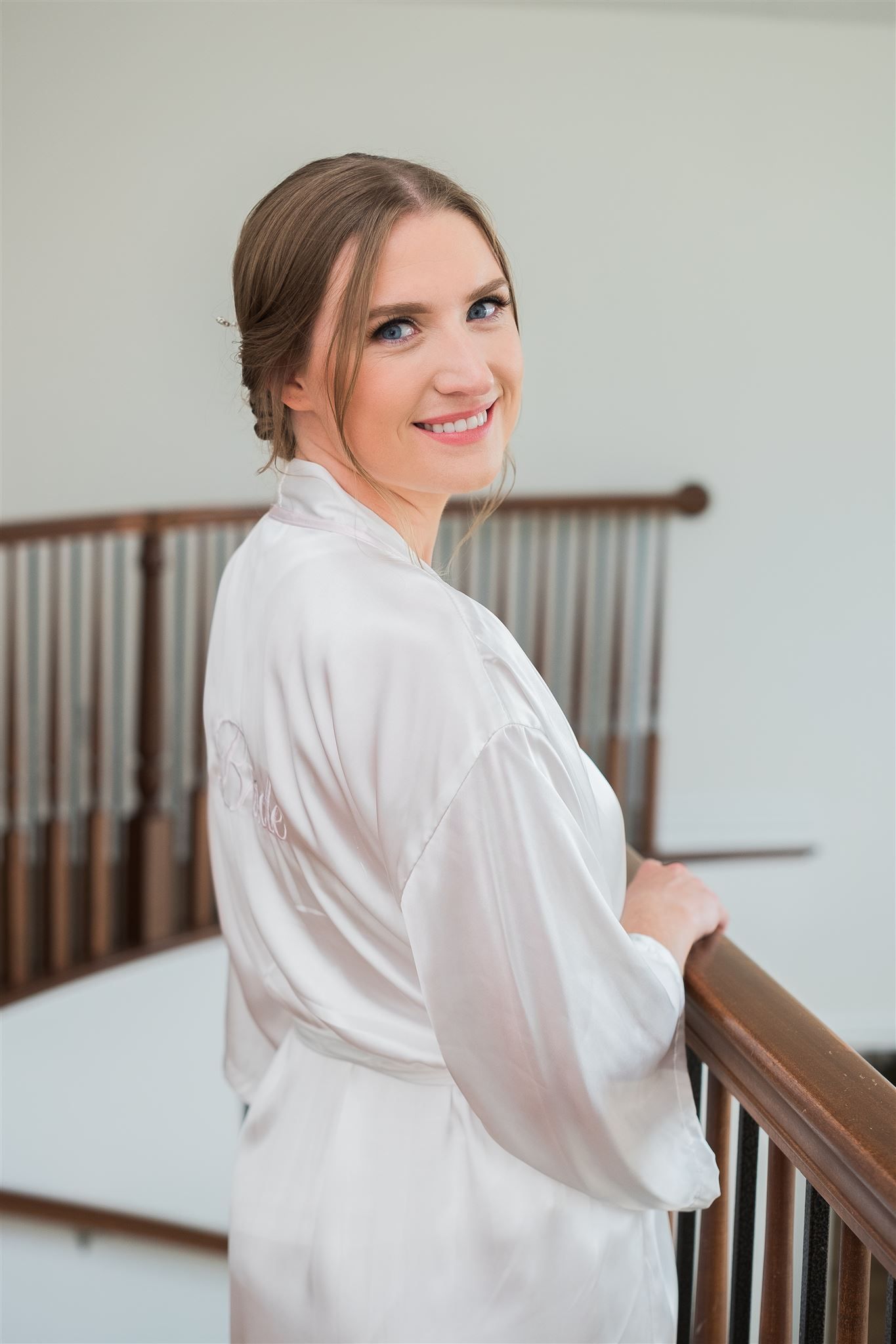 a bride in a white robe is standing on a staircase . natural wedding makeup. pittsburgh, pa. bridal makeup. bridal mua. wedding makeup artist. moriah e beauty. caitlin's living photography.