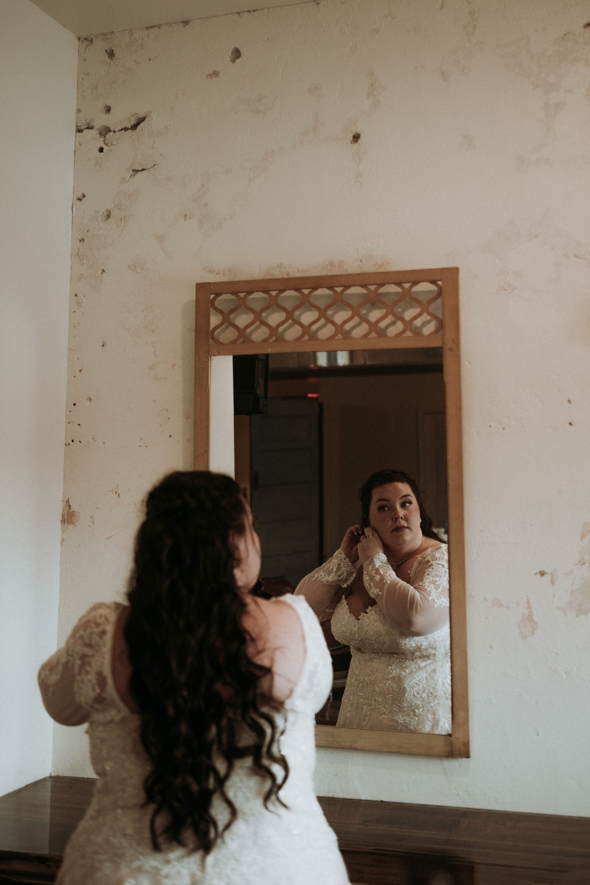 a woman in a wedding dress is looking at her reflection in a mirror . natural wedding makeup. pittsburgh, pa. bridal makeup. bridal mua. wedding makeup artist. moriah e beauty. carlie gabrelcik photography.