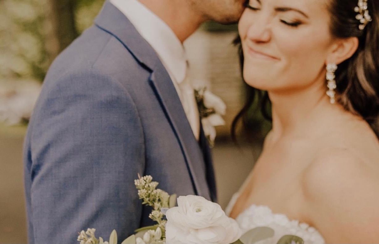 a bride and groom are kissing and the bride is holding a bouquet of flowers . natural wedding makeup. pittsburgh, pa. bridal makeup. bridal mua. wedding makeup artist. moriah e beauty. emily havranek photography.