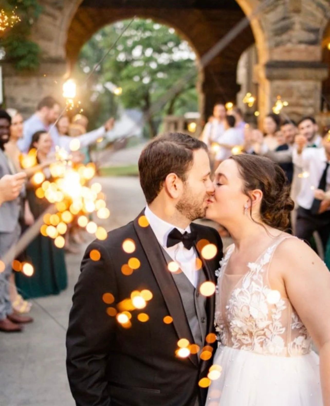 a bride and groom kissing in front of a crowd of people holding sparklers . natural wedding makeup. pittsburgh, pa. bridal makeup. bridal mua. wedding makeup artist. moriah e beauty. danielle durbin film and photo.