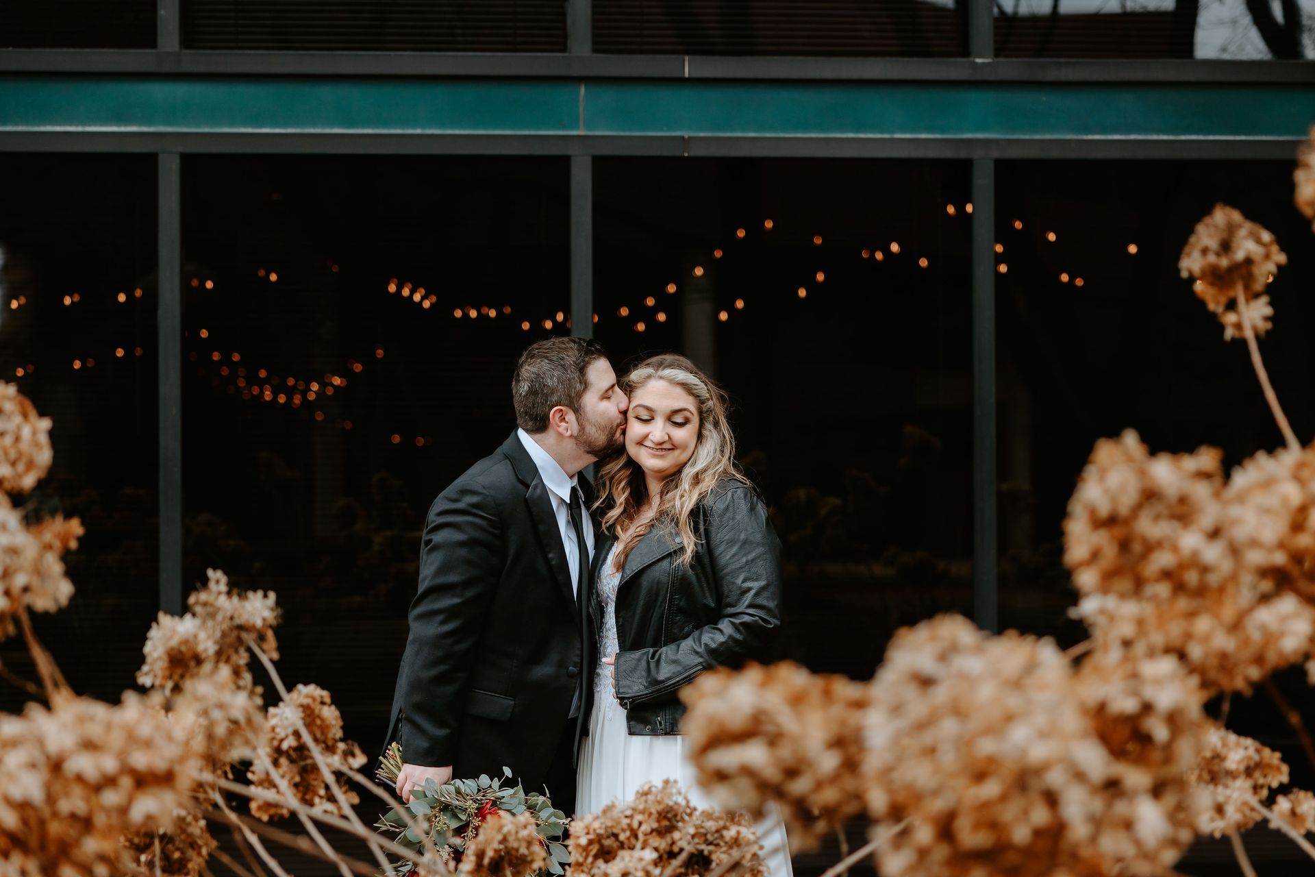 a bride and groom are kissing in front of a building . natural wedding makeup. pittsburgh, pa. bridal makeup. bridal mua. wedding makeup artist. moriah e beauty. liz capuano photography.