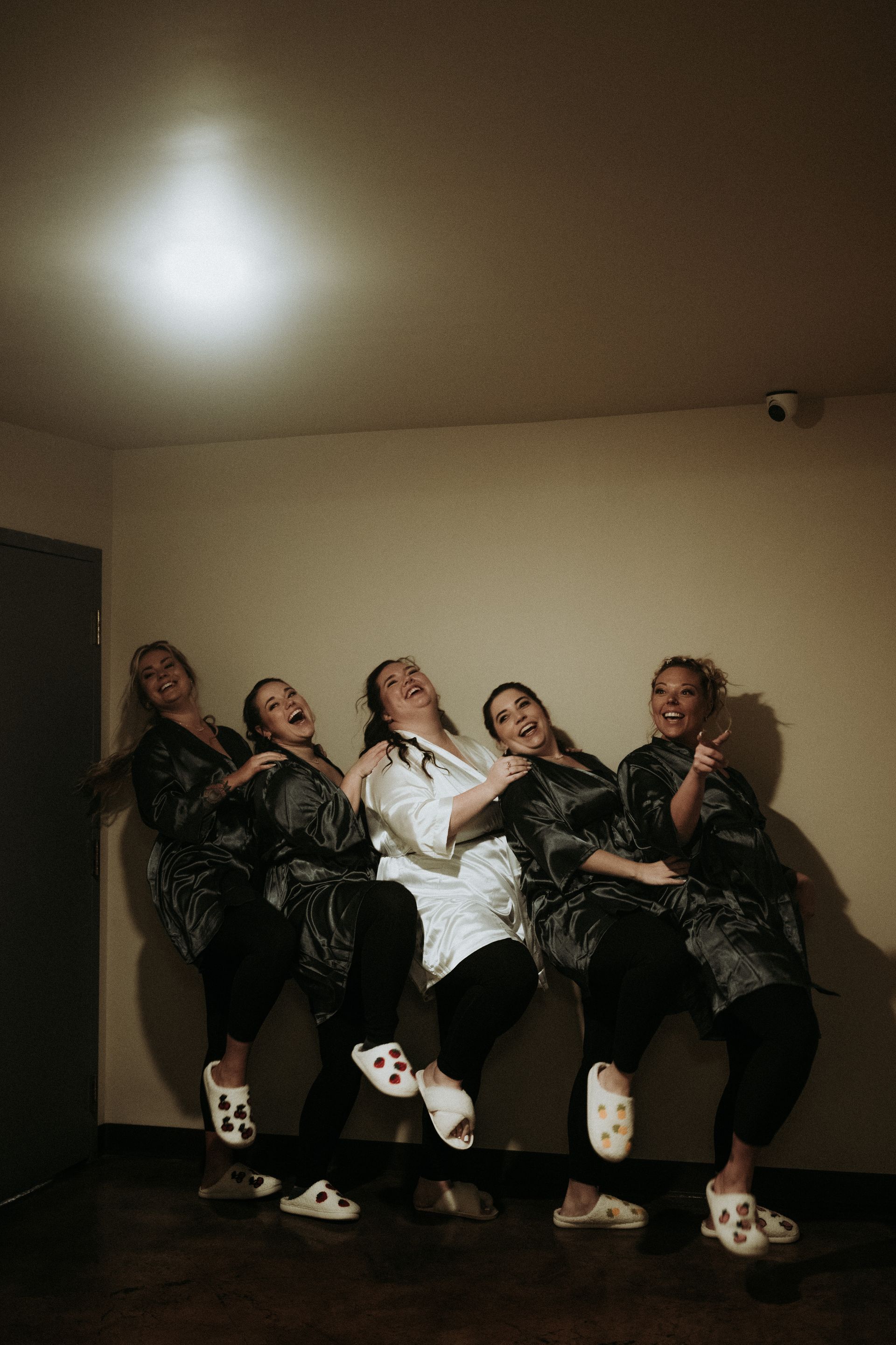 a bride and her bridesmaids have fun posing for pictures in the hallway. natural wedding makeup. pittsburgh, pa. bridal makeup. bridal mua. wedding makeup artist. moriah e beauty. carlie gabrelcik photography.