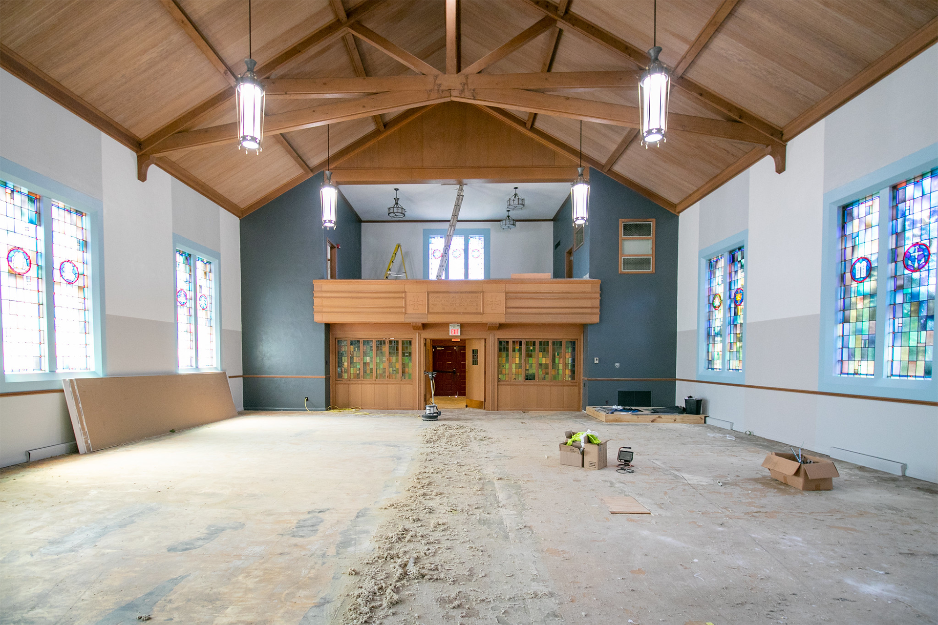 An empty church with stained glass windows and wooden beams