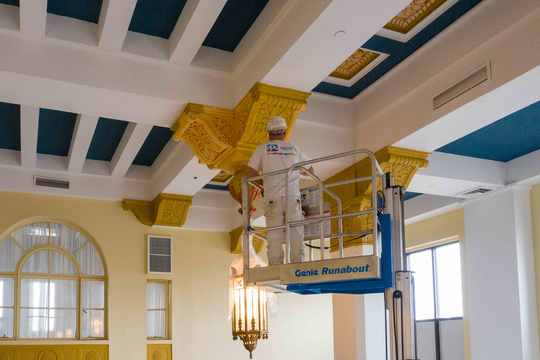 A man is painting the ceiling of a building