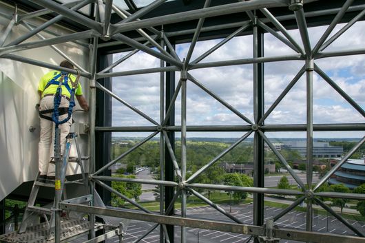 A man is standing on a ladder on top of a building.