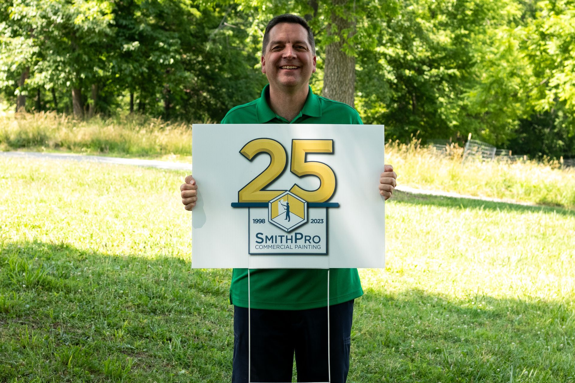 A man in a green shirt is holding a sign with the number 25 on it.