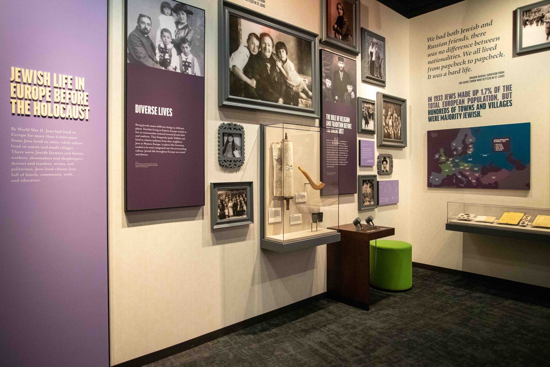 A room with a lot of pictures on the wall and a green ottoman.
