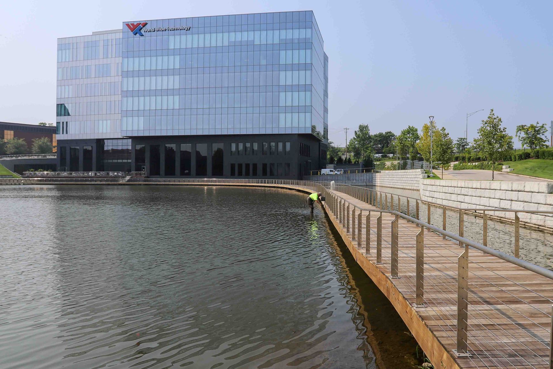 Modern glass office building beside waterfront; SmithPro worker painting the dock & railing.
