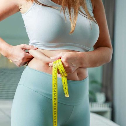 Fatty young woman hand holding excessive belly fat with measure tape, woman diet lifestyle 
