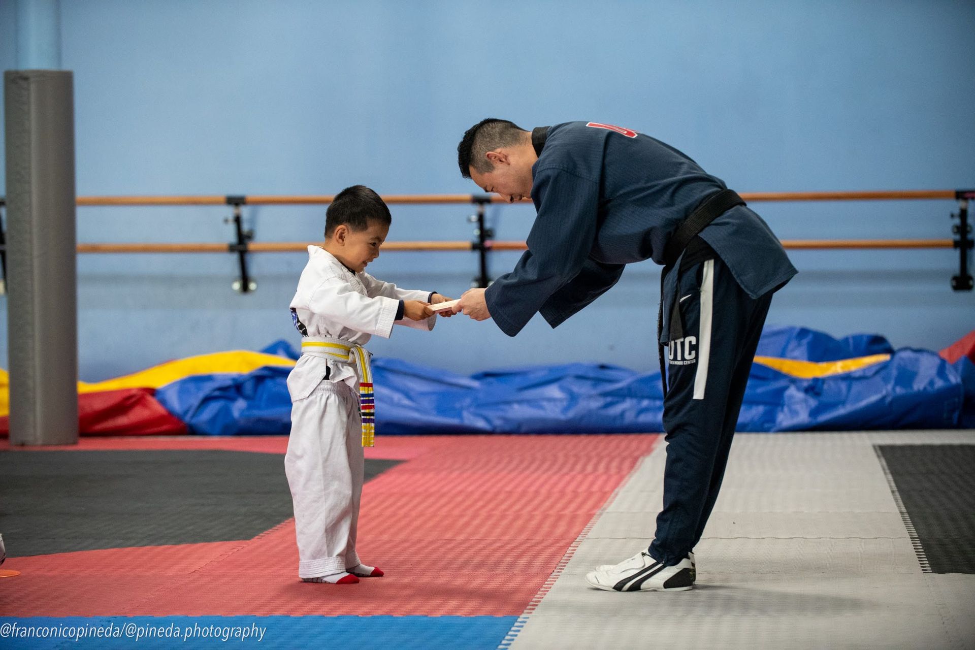 A man is giving a certificate to a young boy in a karate uniform.