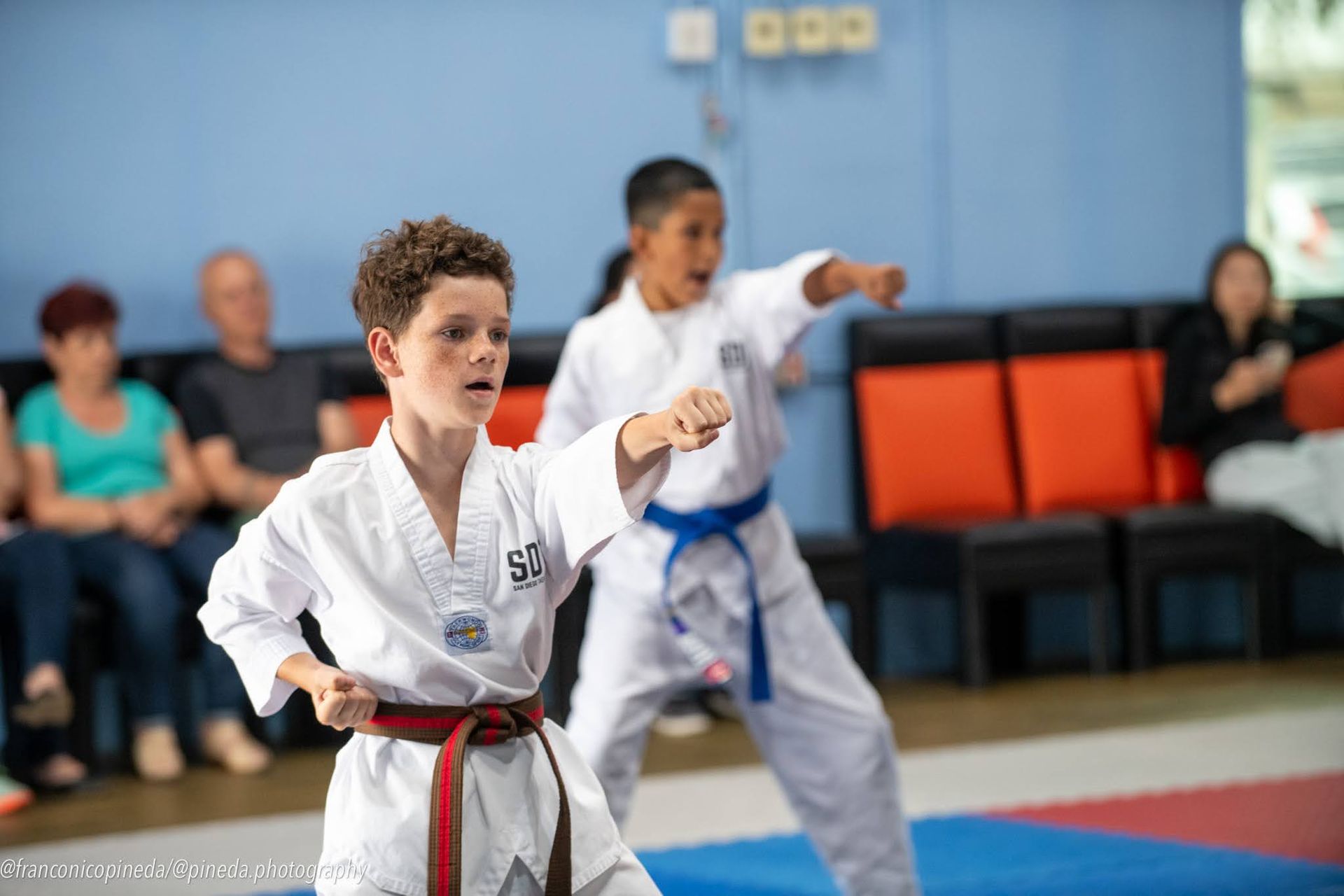 Two young boys are practicing karate in a gym.