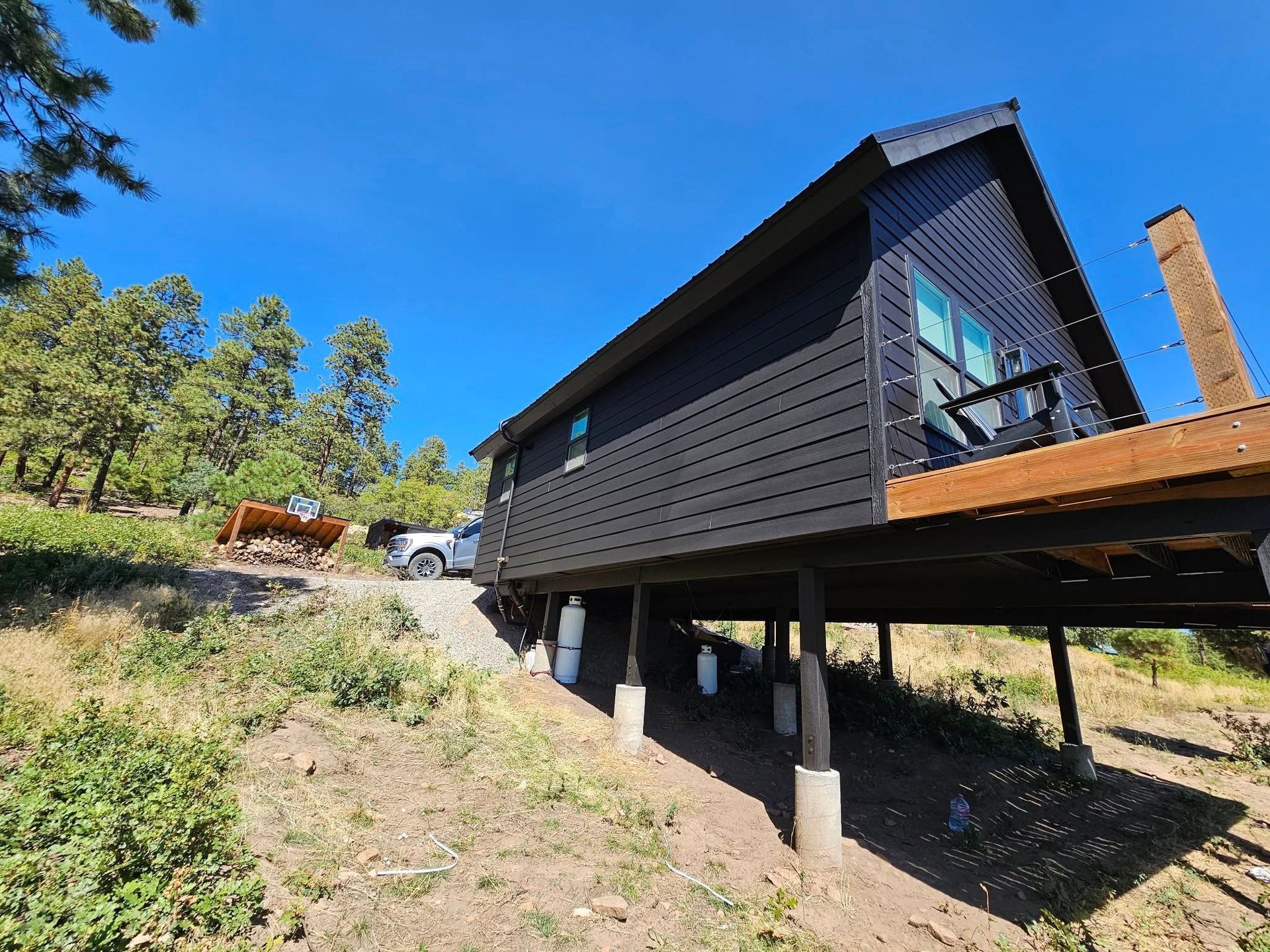 Woman in straw hat smiles, holding wine glass near a lake.
