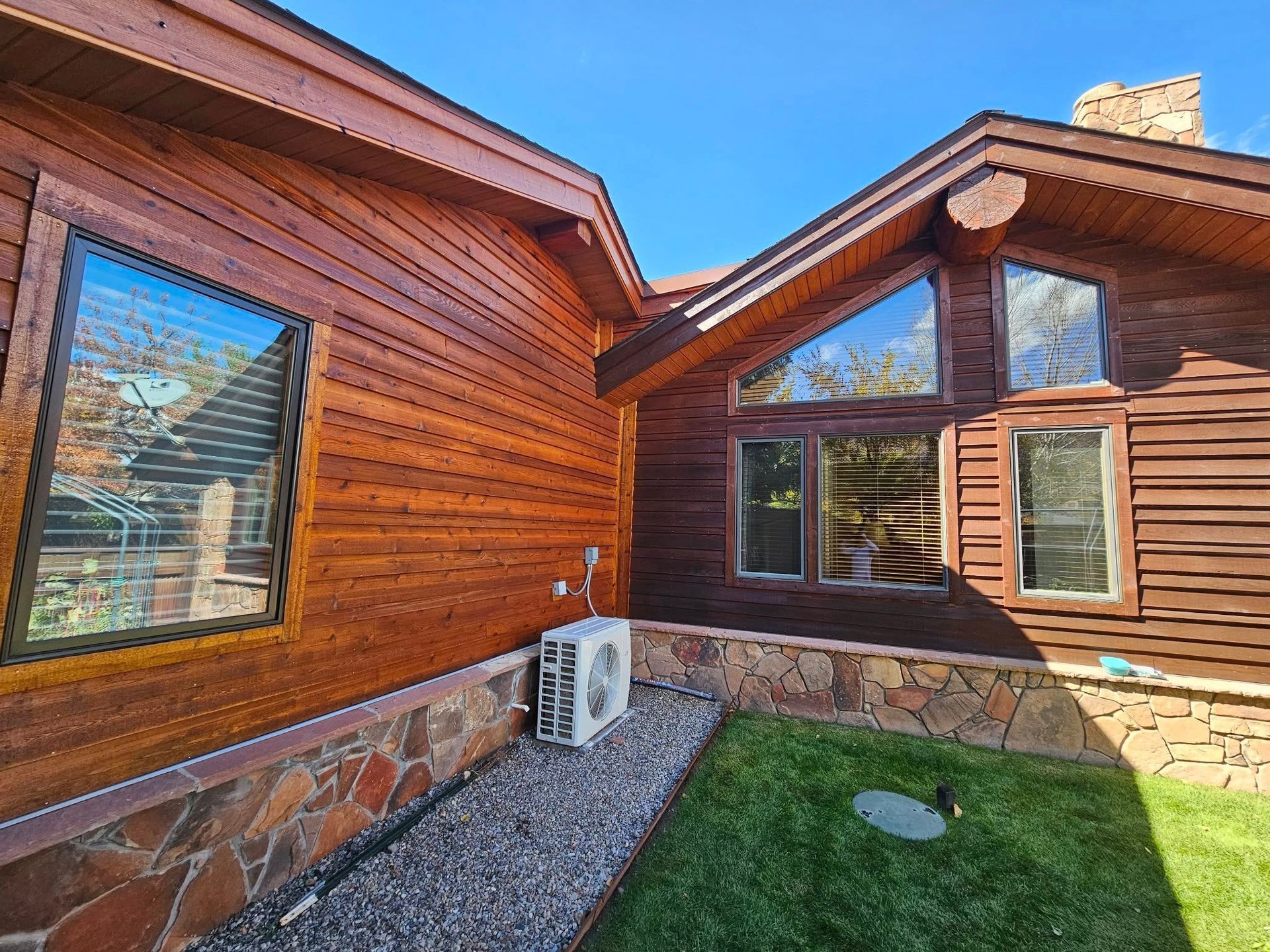 Woman in straw hat smiles, holding wine glass near a lake.