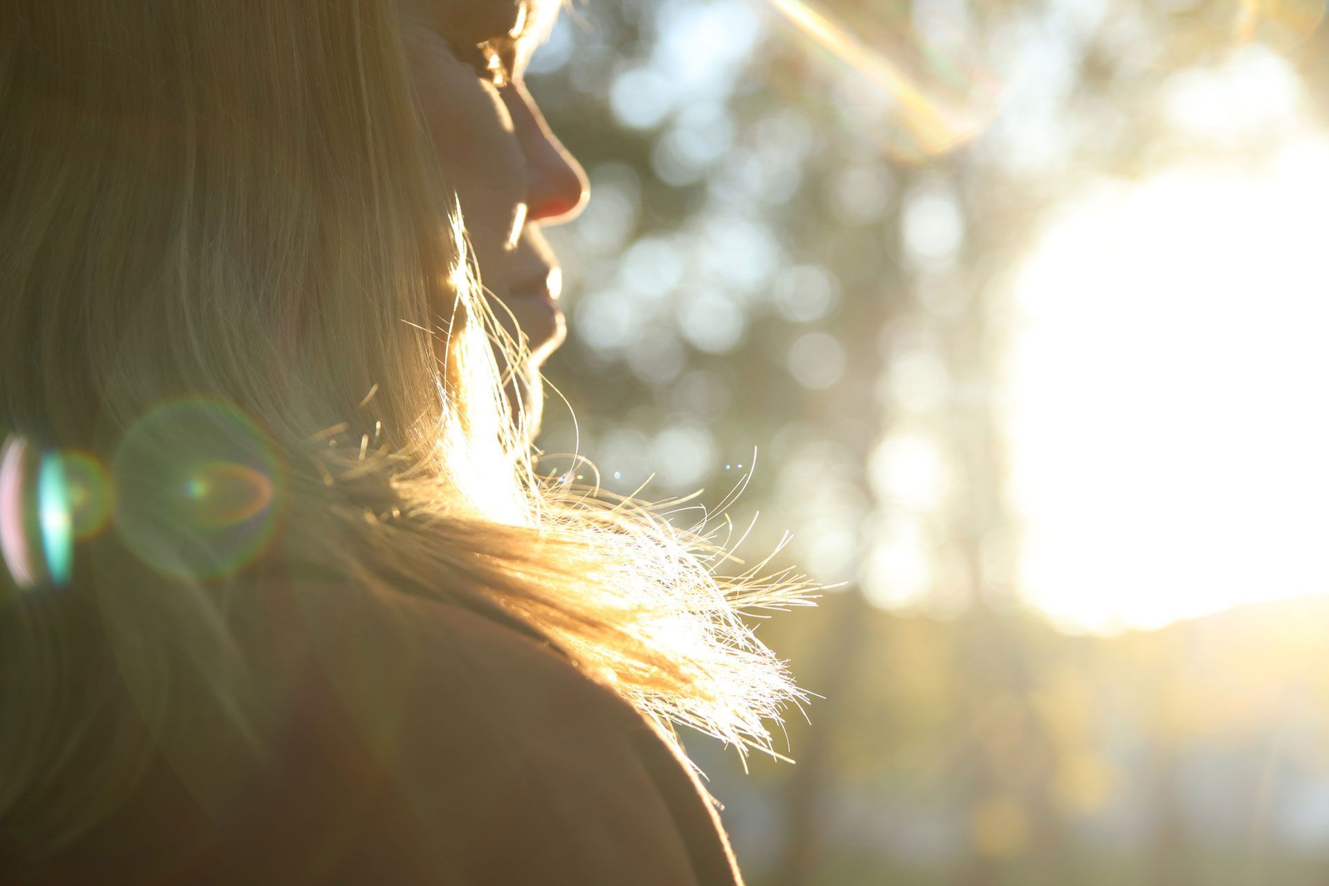 Blonde person in profile, lit by bright sunlight.
