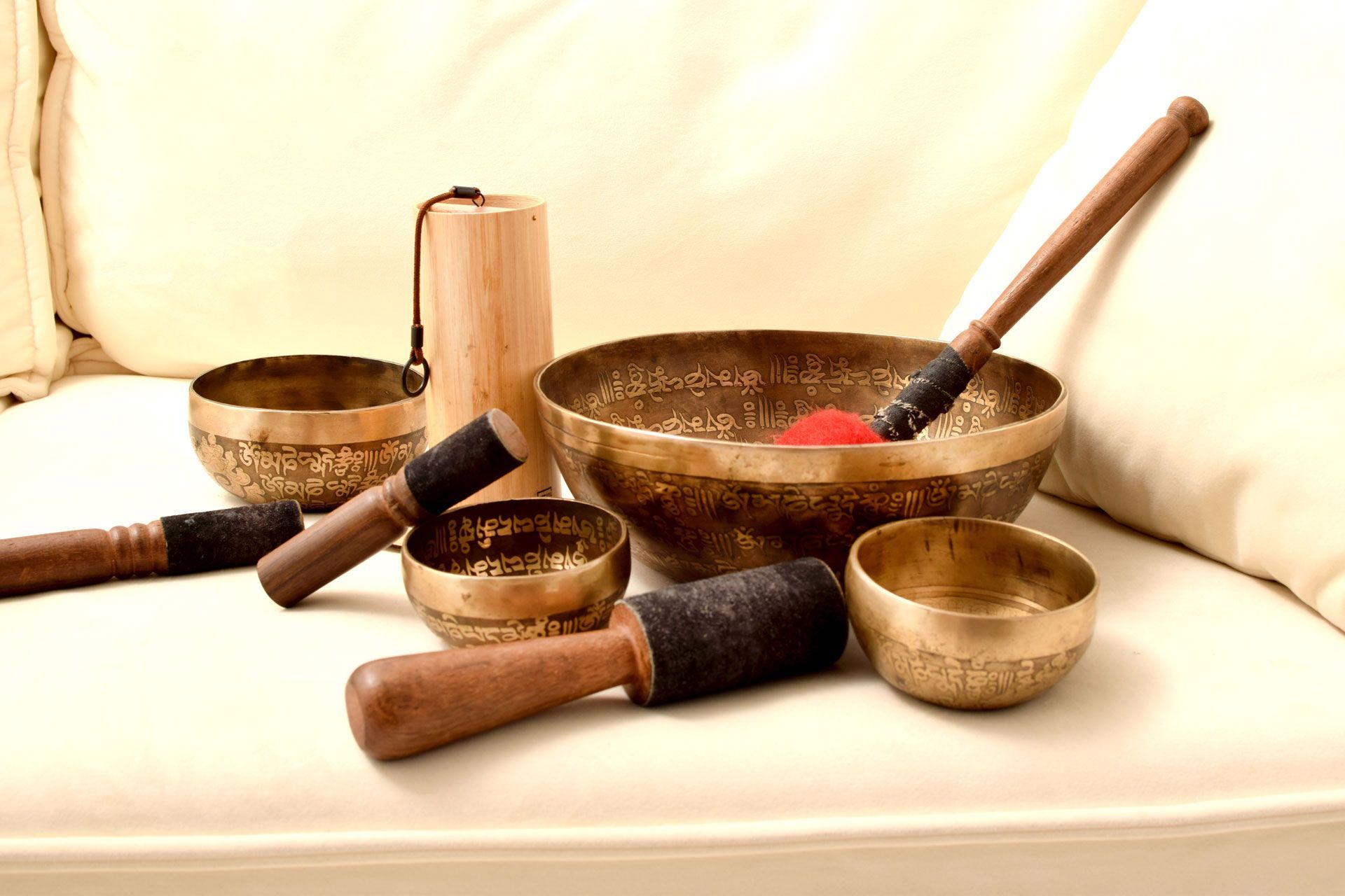 Tibetan singing bowls with wooden strikers on a cream-colored surface.