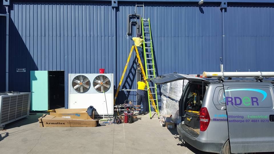 Expert Technician standing on Ladder on work doing Maintenance work of Air Conditioner — Electrician Near Me in NSW
