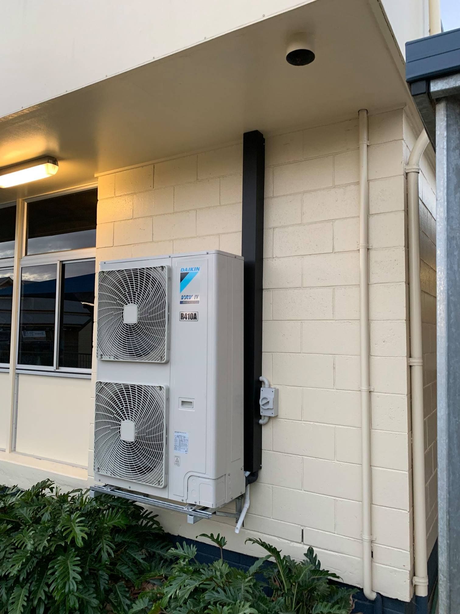 Outdoor unit of AC are installed on roof and a technician is repairing one — Air Conditioning in Warwick