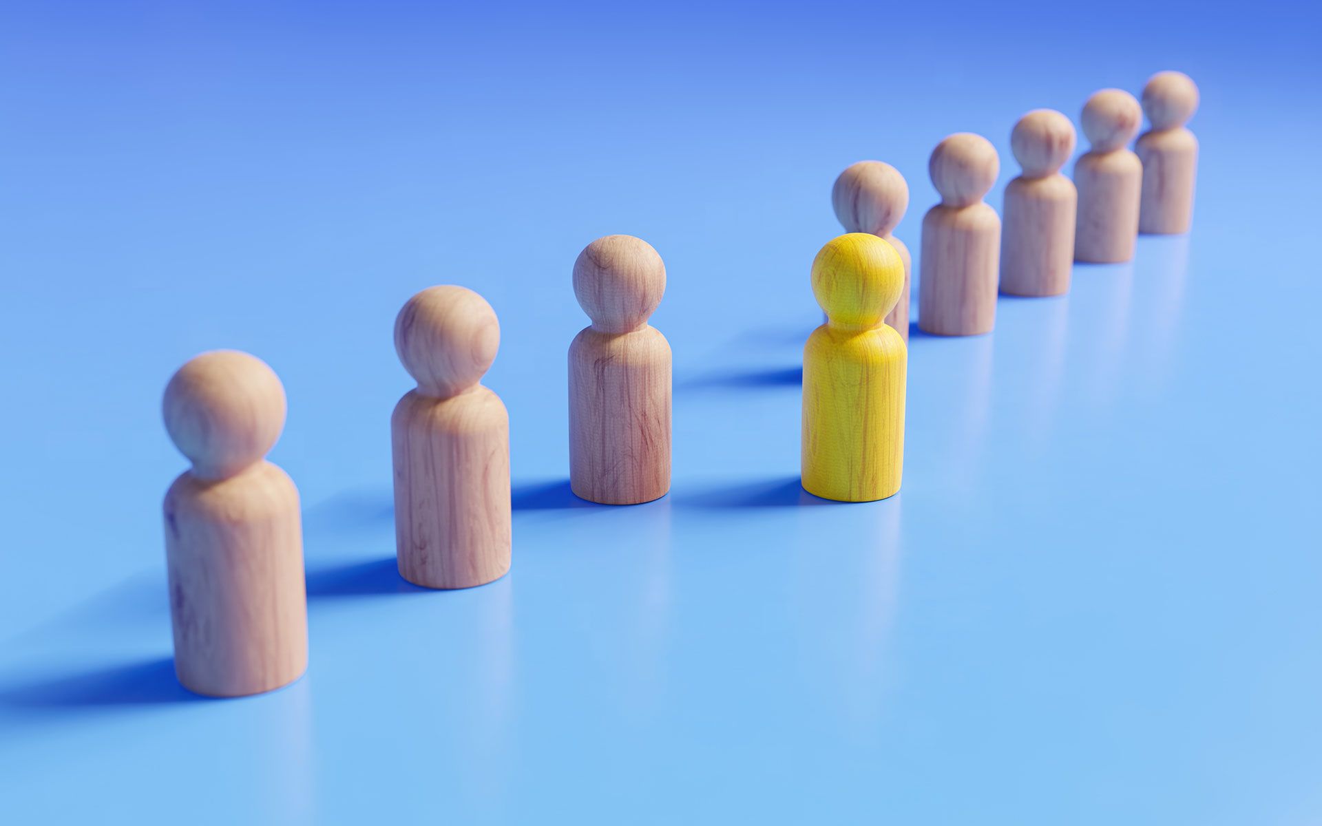 A row of wooden people standing next to each other on a blue surface.