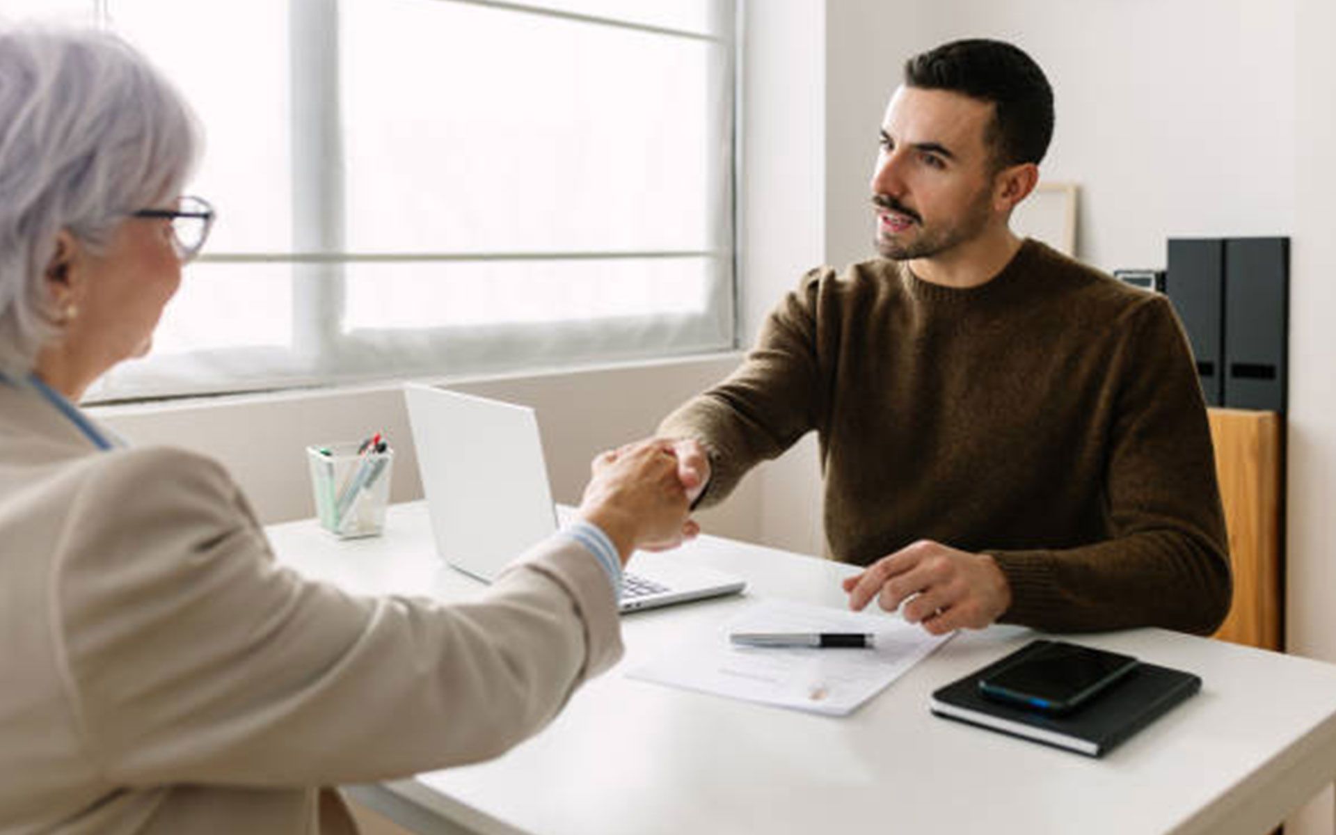 A man and a woman are shaking hands during a job interview.