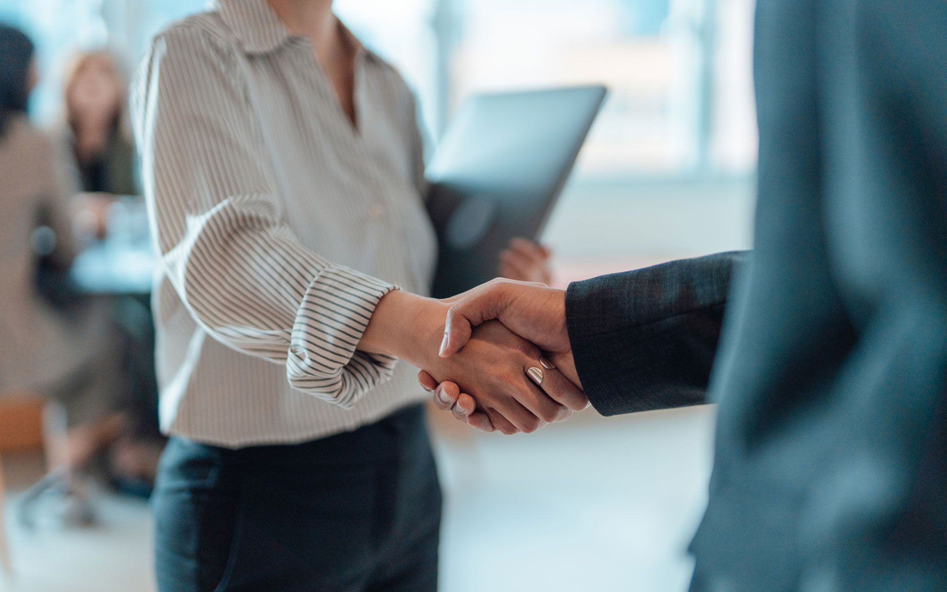 A man and a woman are shaking hands in an office.