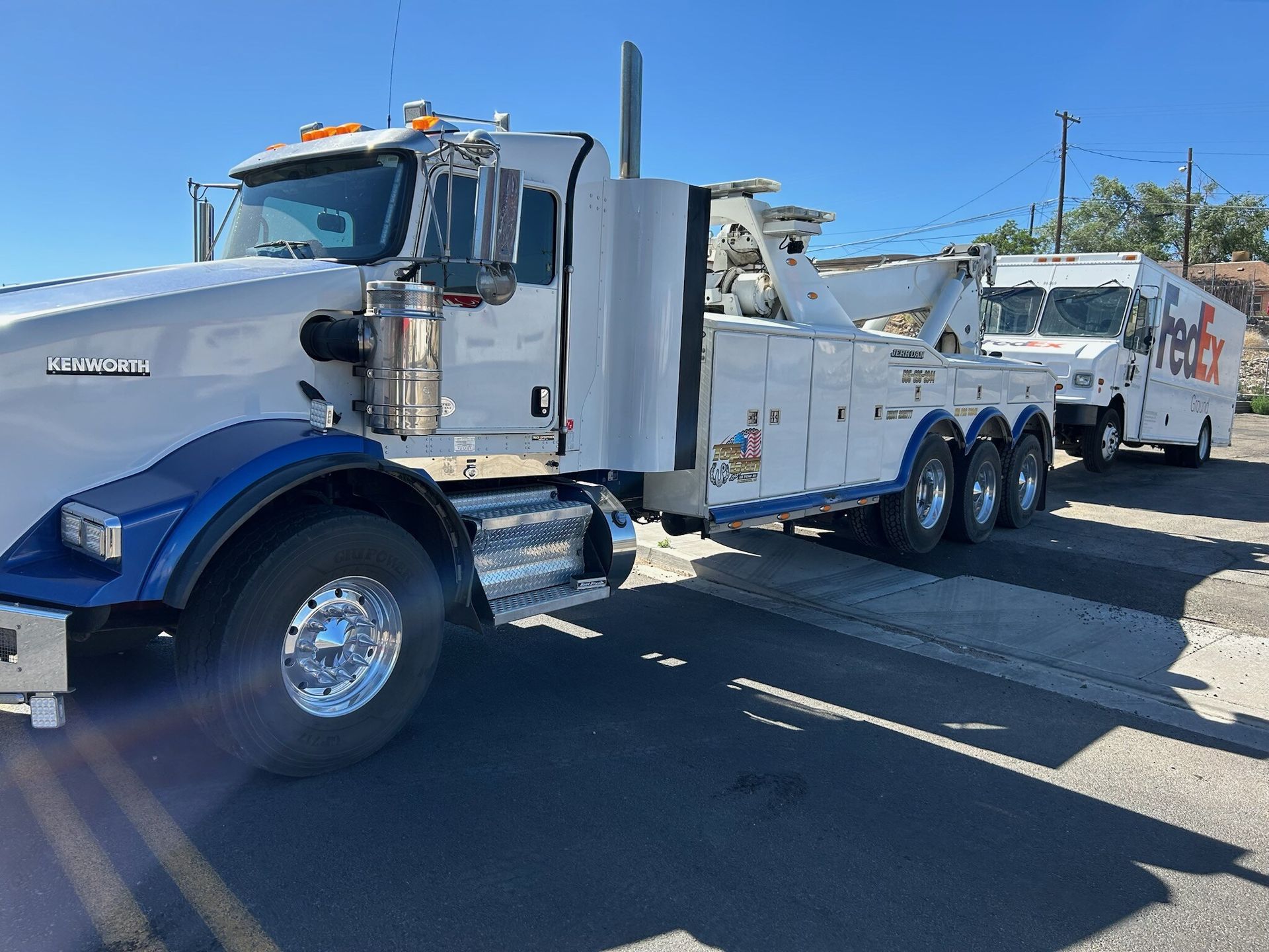 Two tow trucks are parked next to each other on the side of the road.