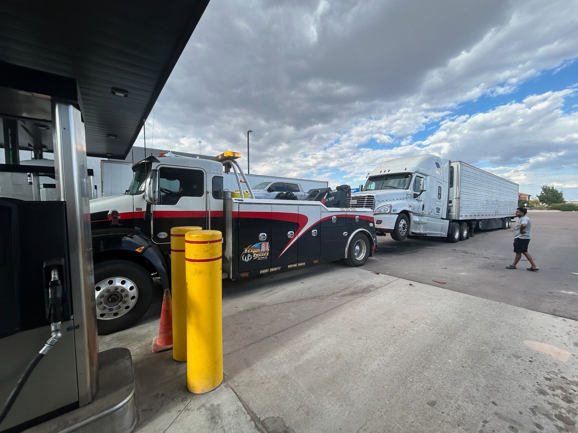 A truck is being towed by a tow truck in a parking lot.
