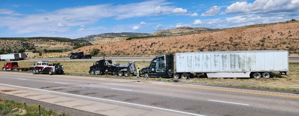 A group of semi trucks are driving down a highway.