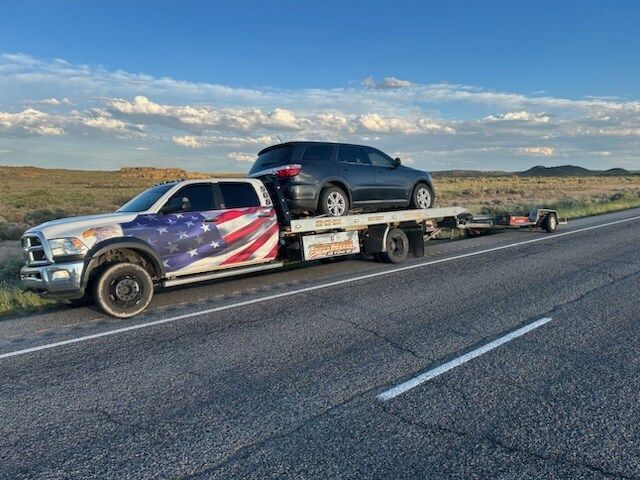 A tow truck is carrying a car on the back of it.