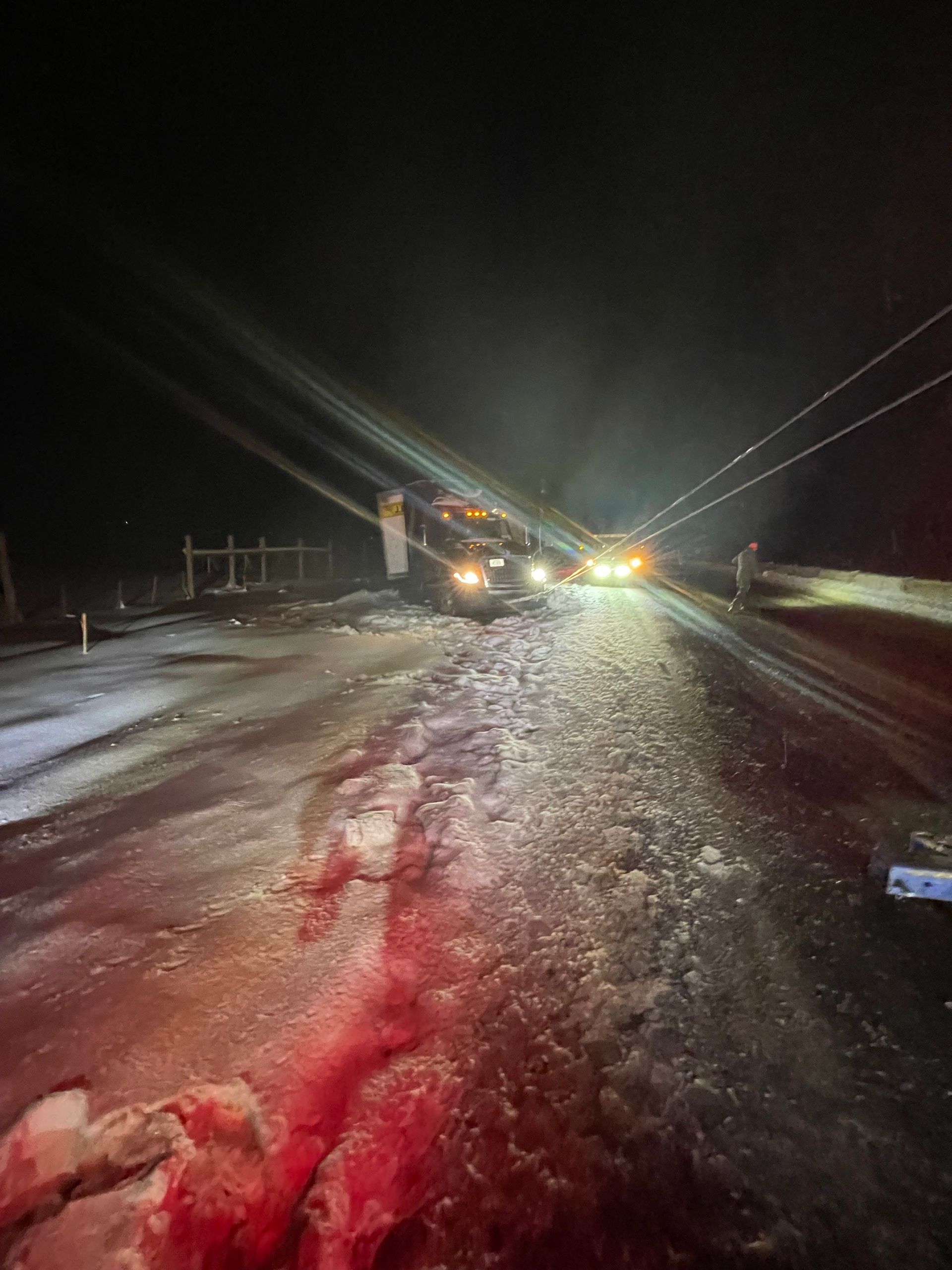 A car is driving down a snowy road at night.