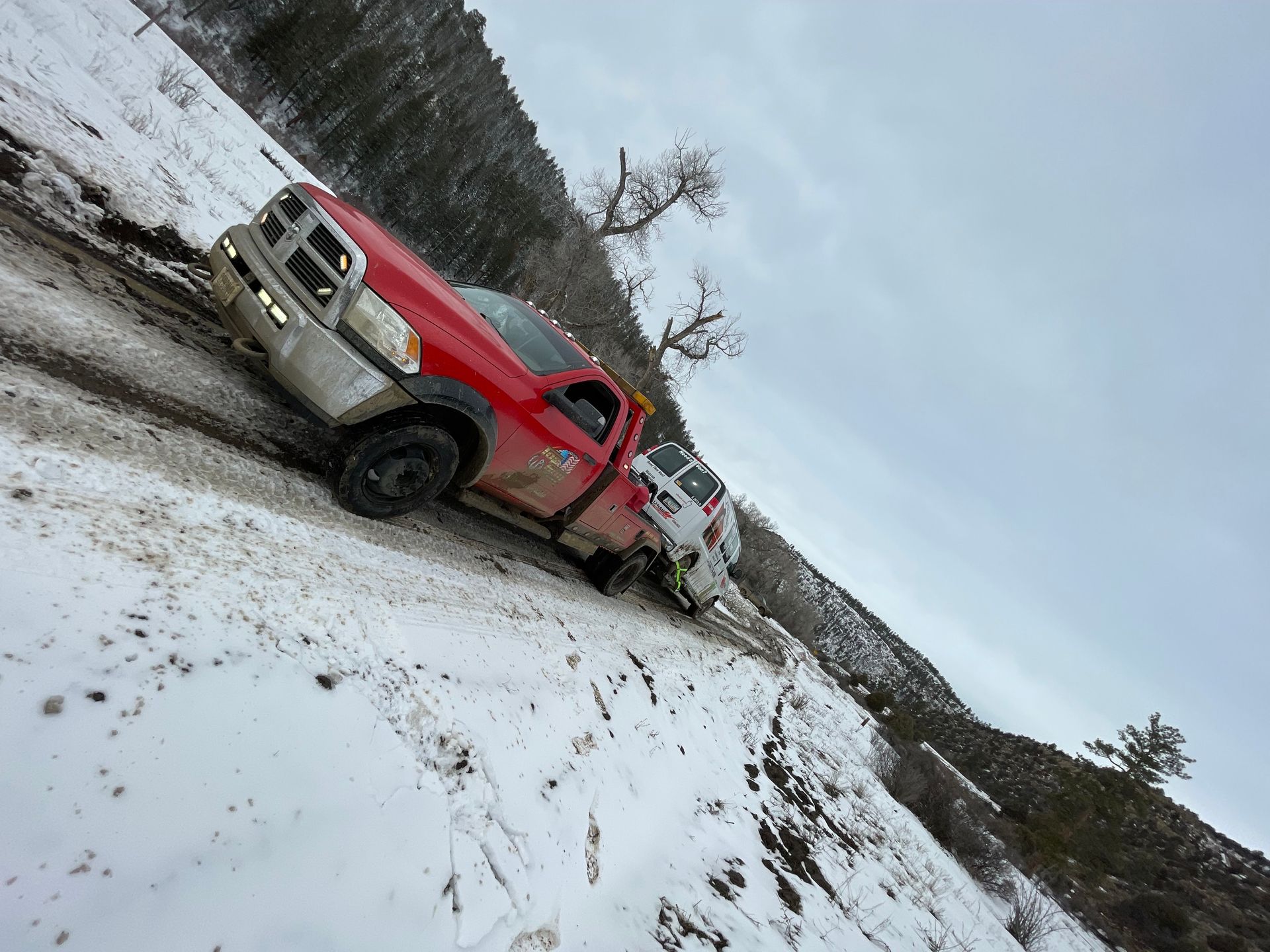 A red truck is driving down a snowy hill.