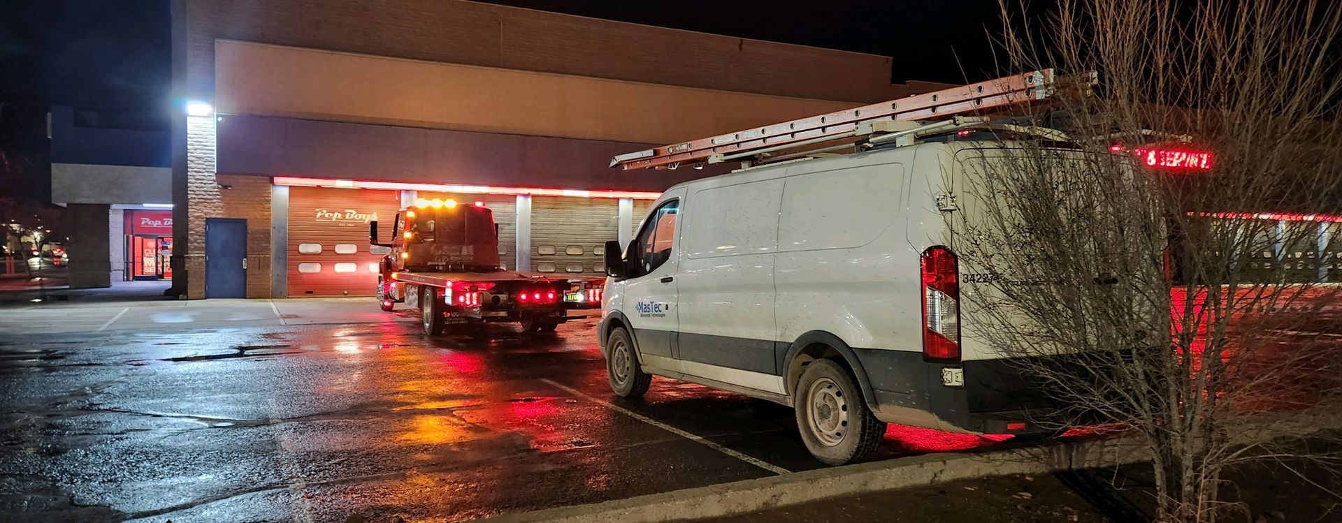 A white van is parked in front of a fire station at night.