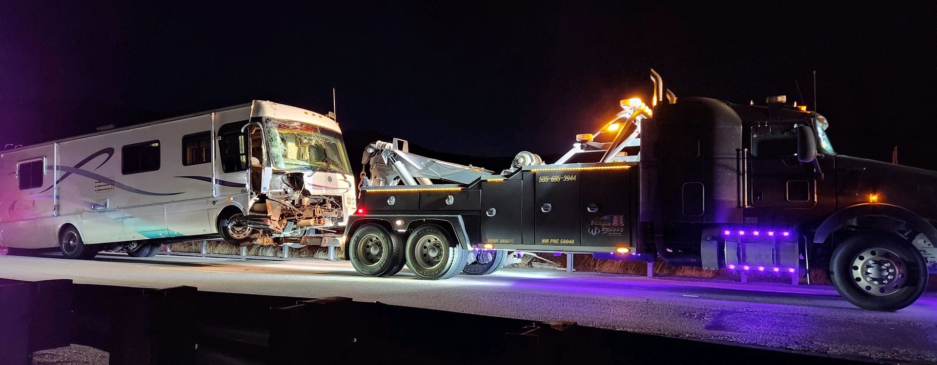 A rv is being towed by a tow truck at night.