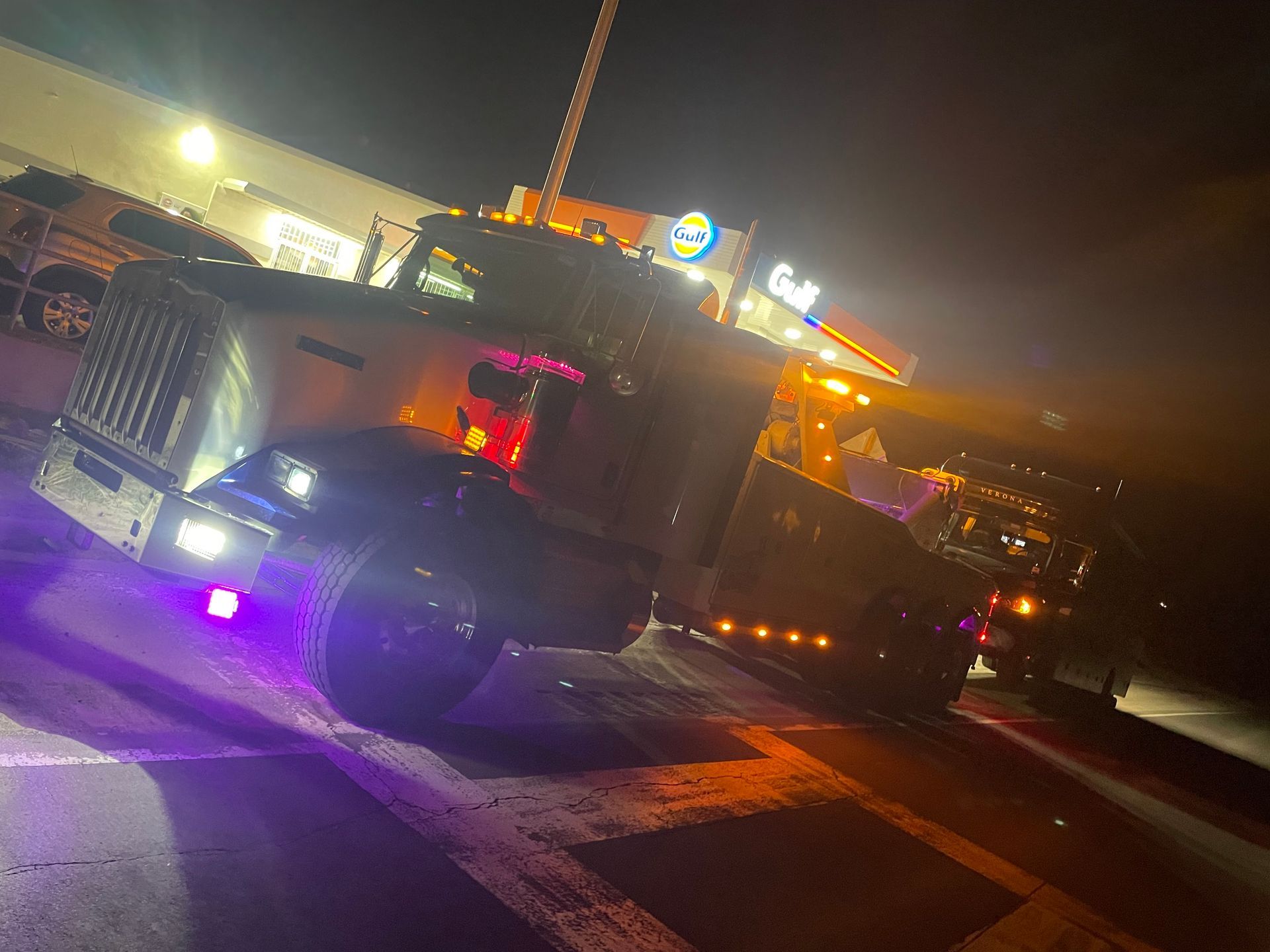 A tow truck is parked on the side of the road at night.