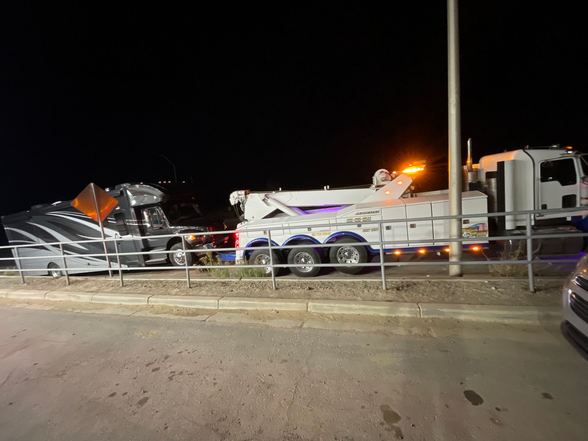 A tow truck is parked on the side of the road at night.
