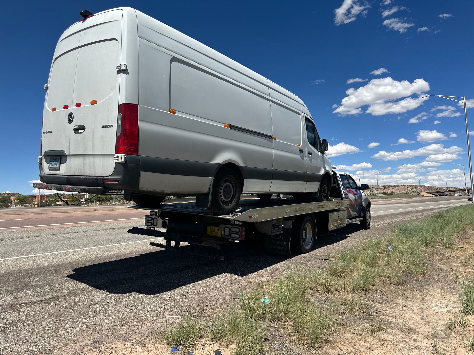 A white van is being towed by a tow truck.