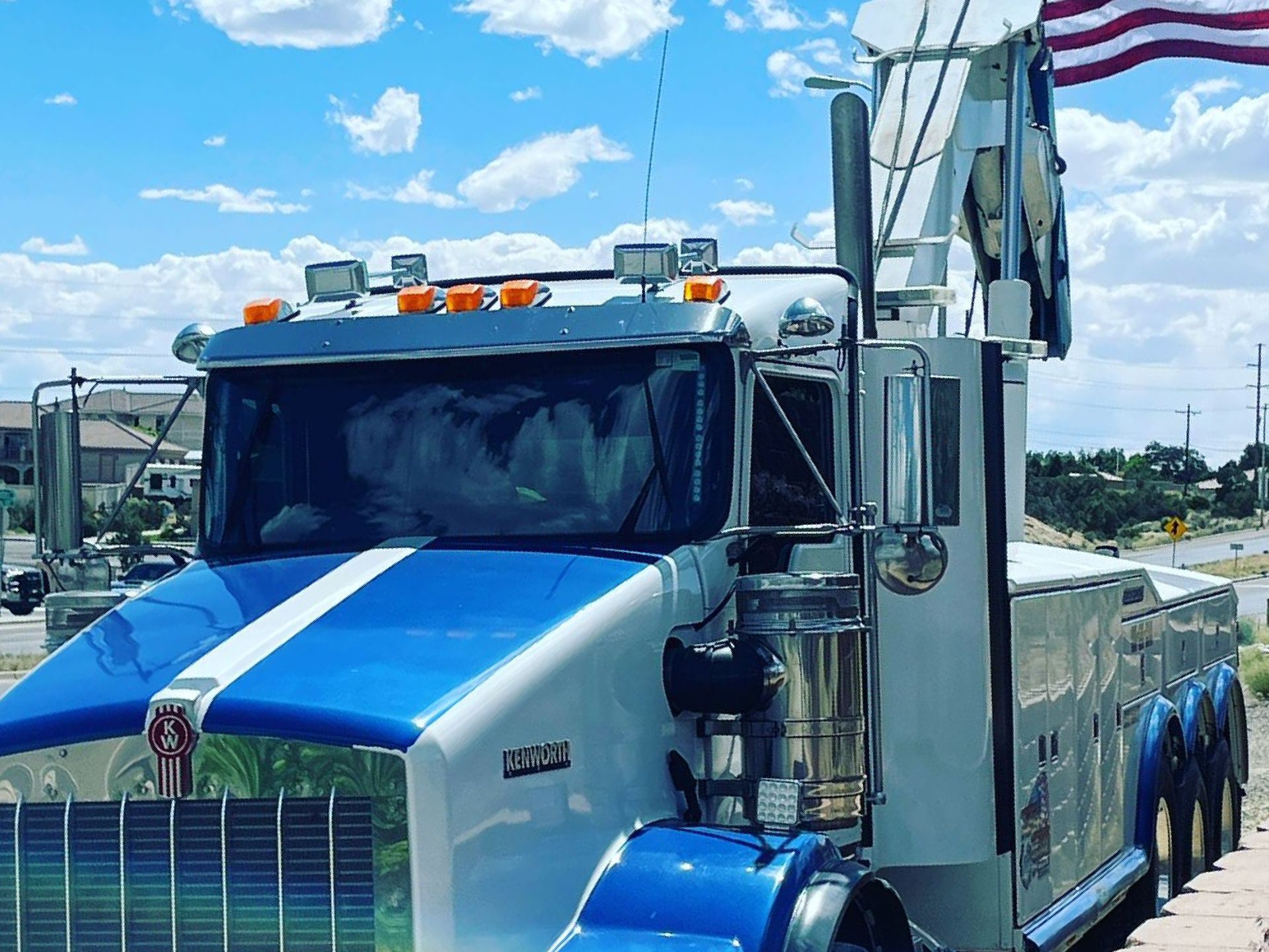 A blue and white tow truck is parked on the side of the road.